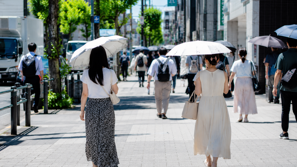 Pessoas caminhando no Japão no verão usando proteção contra o sol